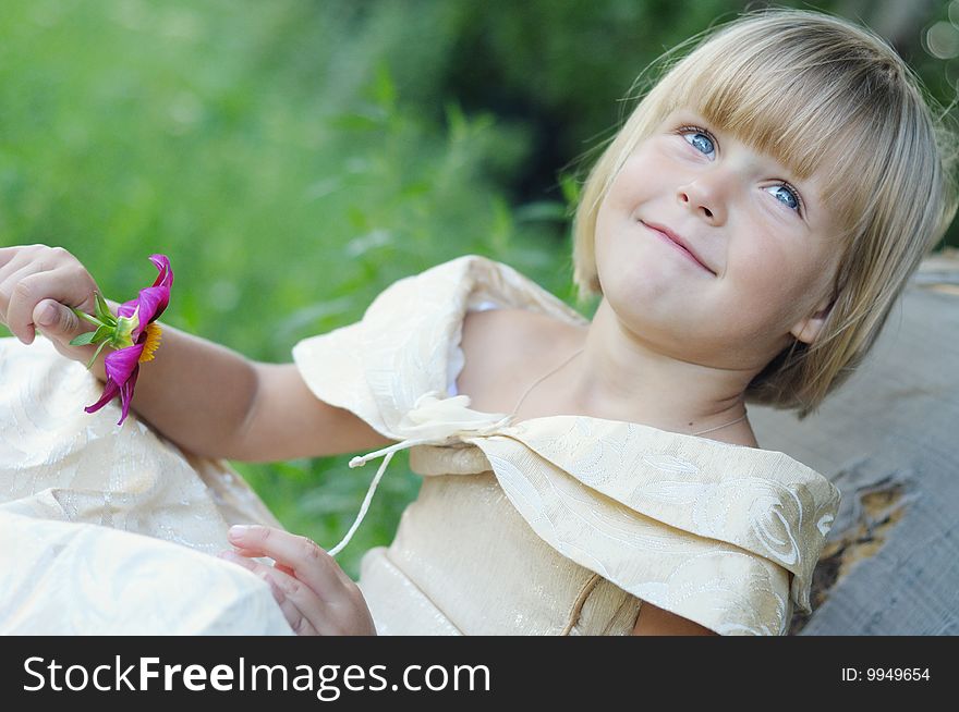 The cute little girl in a beautiful dress, in hand a flower. The cute little girl in a beautiful dress, in hand a flower.