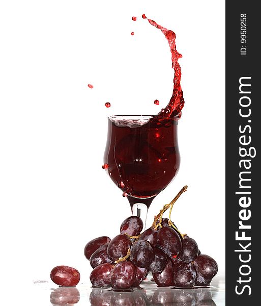 Goblet with splashing red wine standing near bunch of grapes. Isolated with clipping path