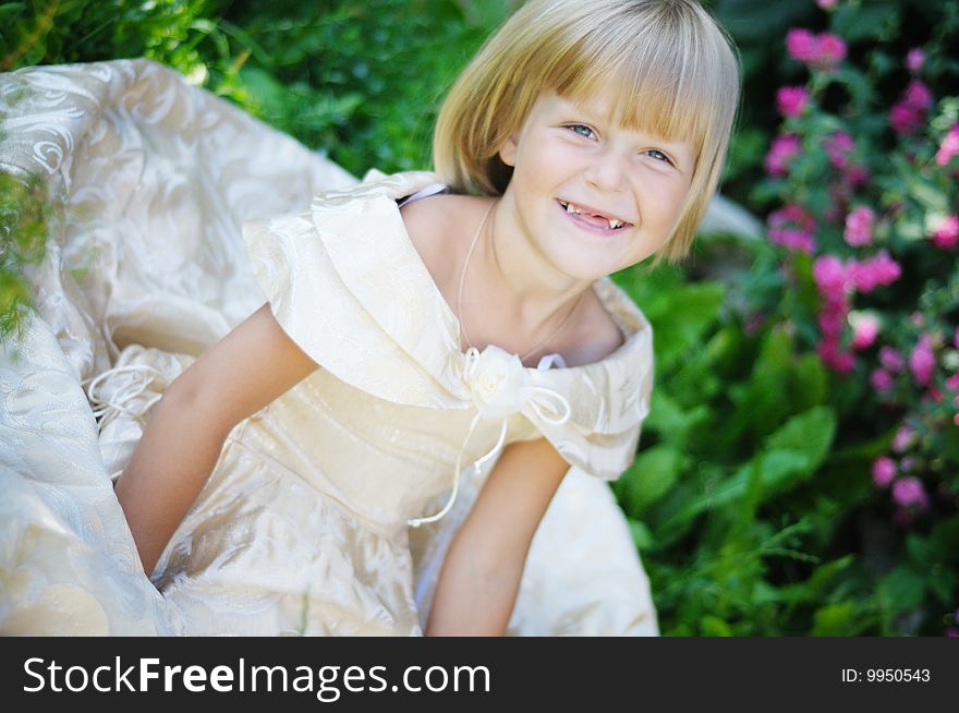 The girl the blonde in a beautiful dress sits on a grass. The girl the blonde in a beautiful dress sits on a grass