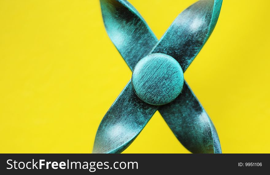Abstract turquoise colored metal application in cross shape with yellow background and copy space. Abstract turquoise colored metal application in cross shape with yellow background and copy space.
