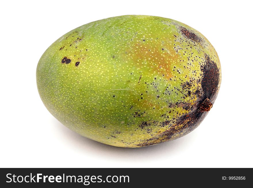 A large green uncut mango fruit on white surface. A large green uncut mango fruit on white surface