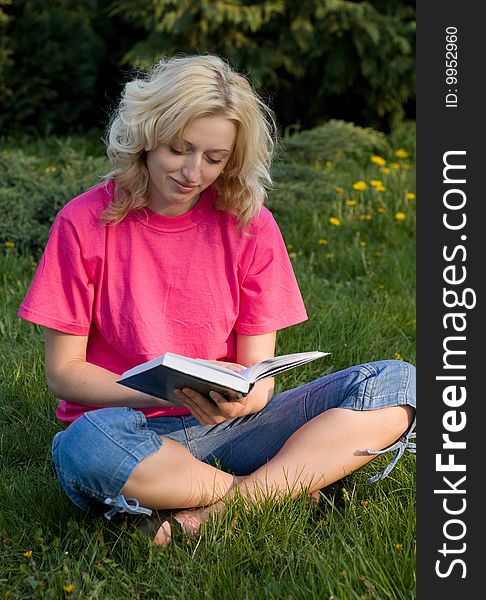 Girl reading book on a grass