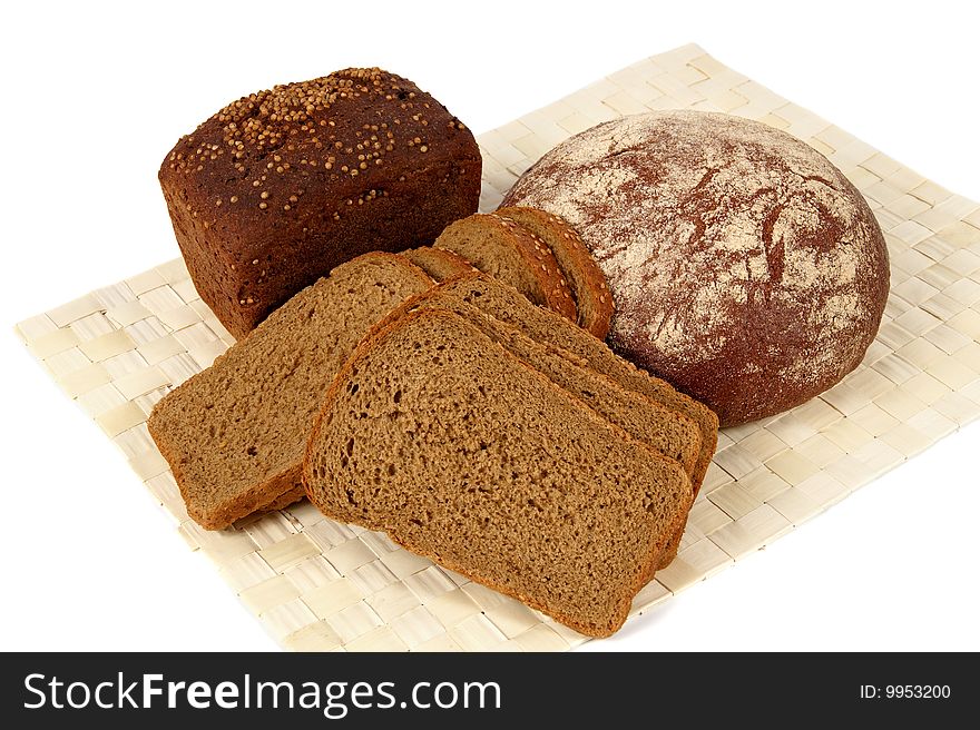 There are three types of rye bread in the picture. One loaf of bread that is on the left is covered by coriander. There are three types of rye bread in the picture. One loaf of bread that is on the left is covered by coriander.