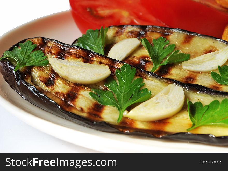 Grilled aubergine served with garlic on white plate. Grilled aubergine served with garlic on white plate