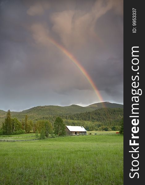 Rainbow over a barn in a field.