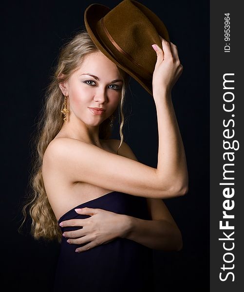 Portrait of young pretty girl with a hat on dark background.