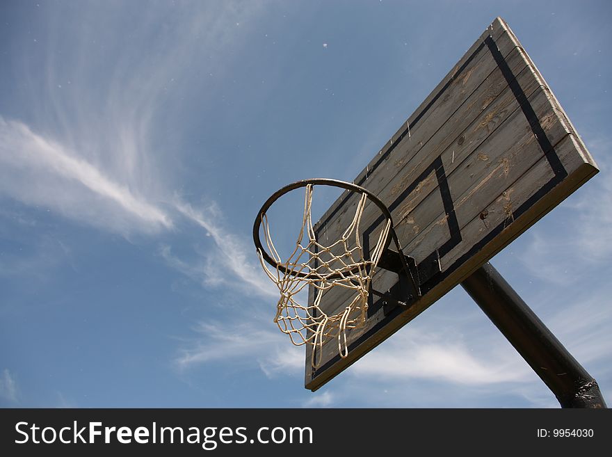 Old worn-out basketball board in the cloudy blue sky. Old worn-out basketball board in the cloudy blue sky