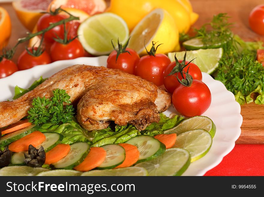 Fried chicken leg with lemon and cucumber on a plate