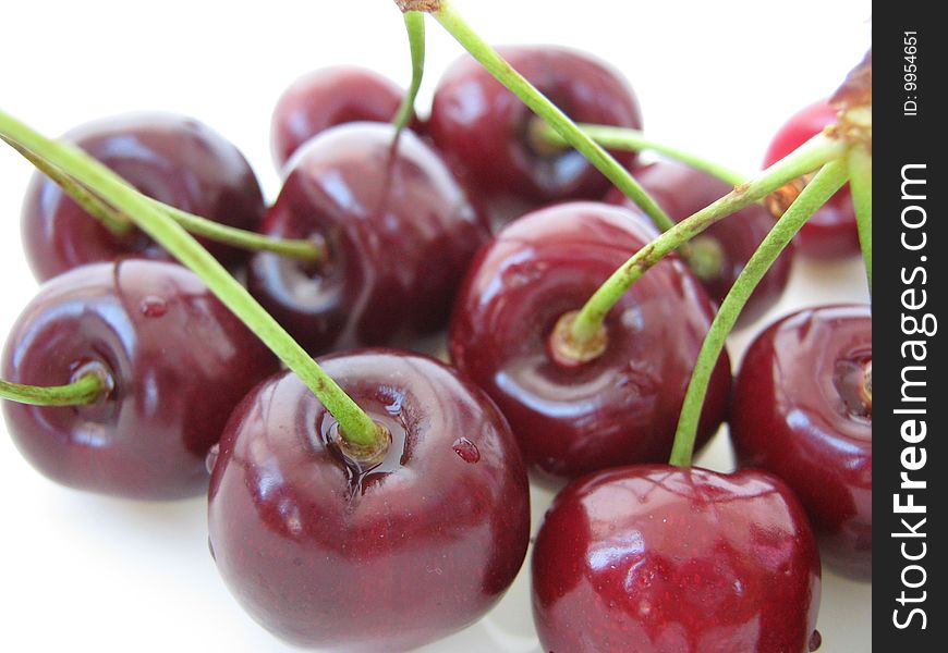 Closeup of red shiny cherries on white background.