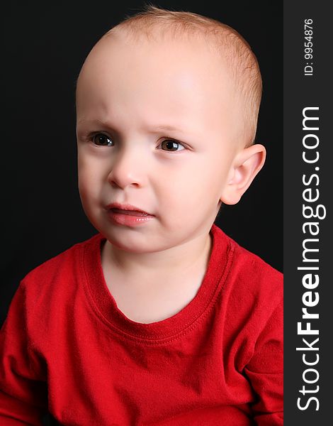 Cute toddler wearing a red shirt with a frown