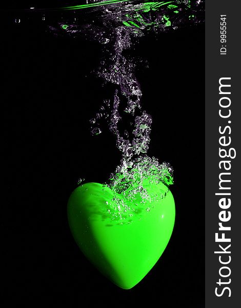 Green heart splashing underwater against black background. Green heart splashing underwater against black background