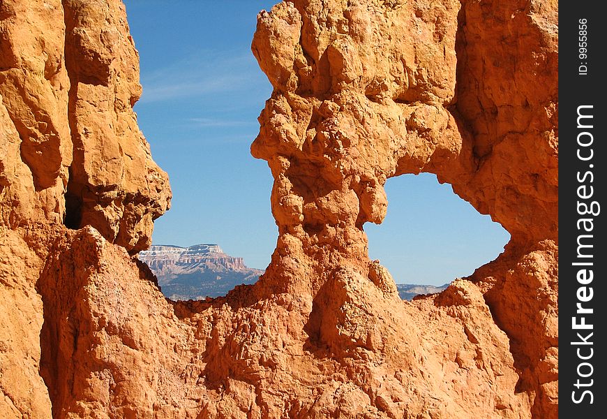 Mountains framed by the holes in the multicoloured Hoodoos at Bryce Canyon. Mountains framed by the holes in the multicoloured Hoodoos at Bryce Canyon