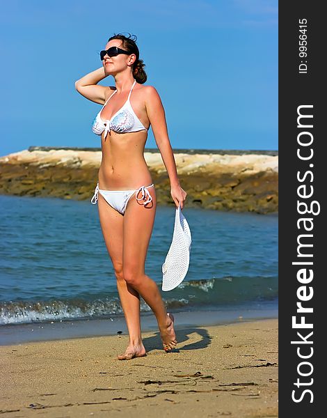 Brunette lady with white hat standing on the beach. Brunette lady with white hat standing on the beach