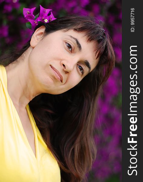 Young woman with flower in her hair against violet flowers background. Young woman with flower in her hair against violet flowers background