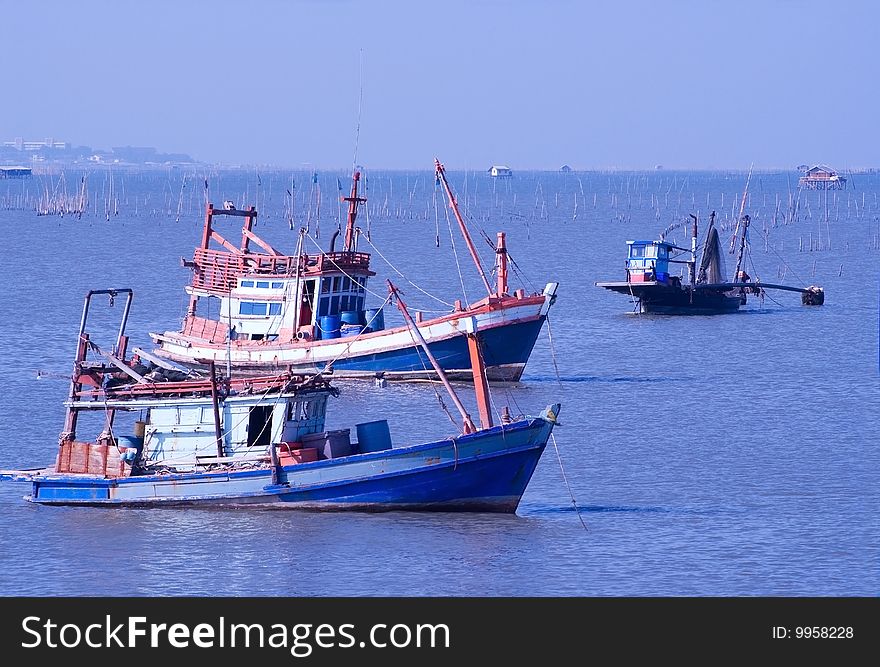 Three blue and orange fishing boats anchored in the Gulf of Siam, in the harbour of Chonburi City. Three blue and orange fishing boats anchored in the Gulf of Siam, in the harbour of Chonburi City.