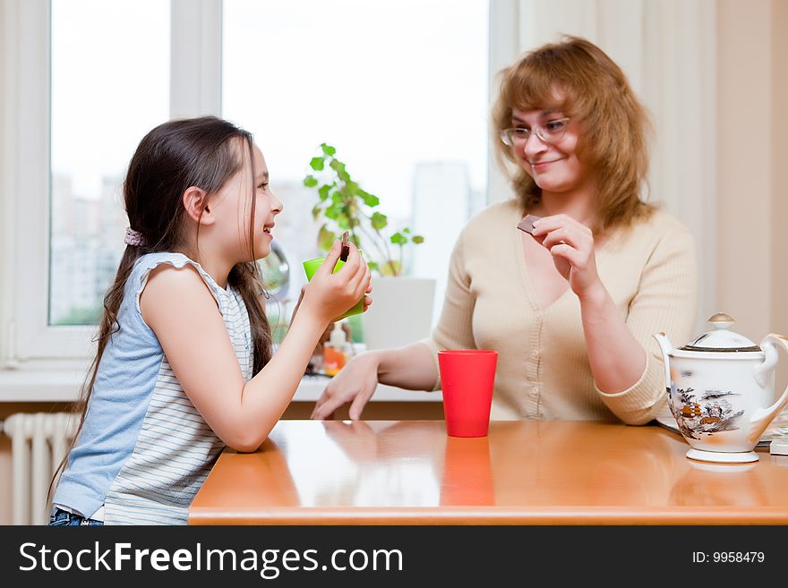 Mother and daughter drink tea behind a table