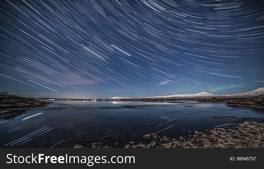 Star trails in night sky over waterfront. Star trails in night sky over waterfront.