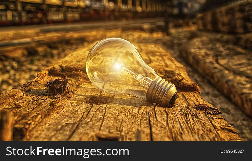 A light bulb with light flare on wood background. A light bulb with light flare on wood background.