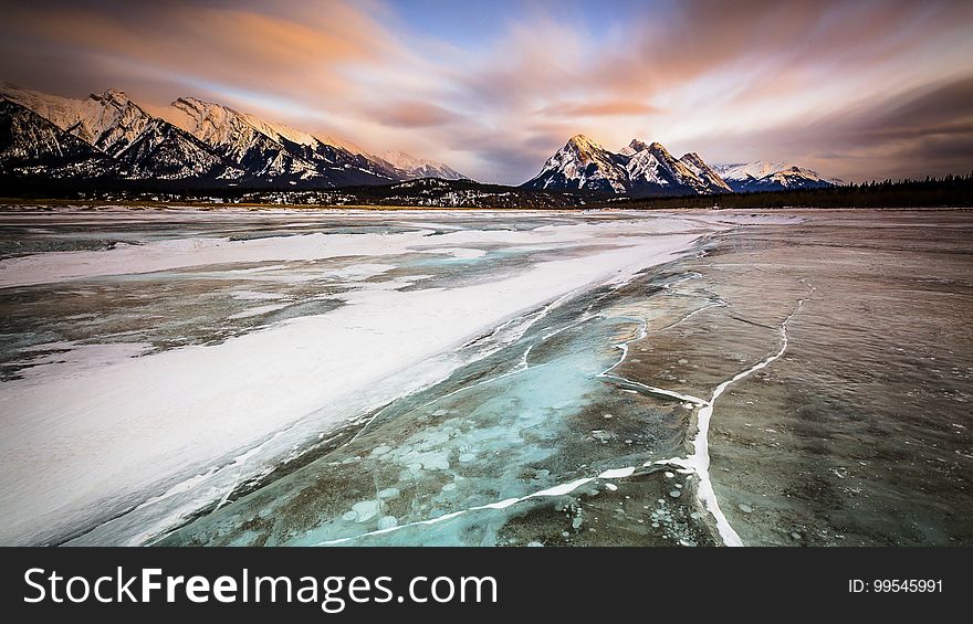 Sunrise over Canadian Rockies with snow and ice in foreground.