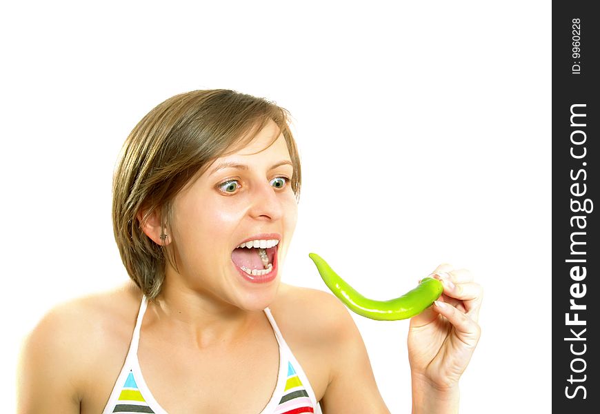 Portrait of a young cute Caucasian blond girl with a nice colorful striped summer dress who is going crazy and she is holding a fresh green chilly pepper in her hand. Isolated on white. Portrait of a young cute Caucasian blond girl with a nice colorful striped summer dress who is going crazy and she is holding a fresh green chilly pepper in her hand. Isolated on white.