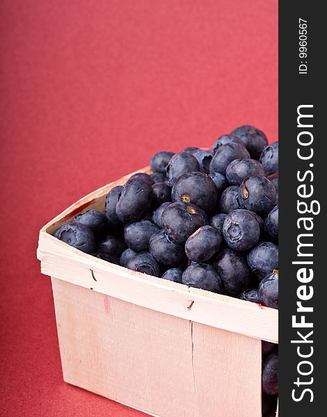 Wooden quart of blueberries on a red background. Wooden quart of blueberries on a red background