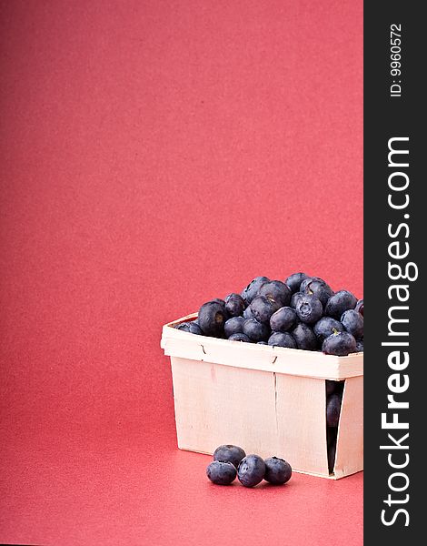 Wooden quart of blueberries on a red background. Wooden quart of blueberries on a red background