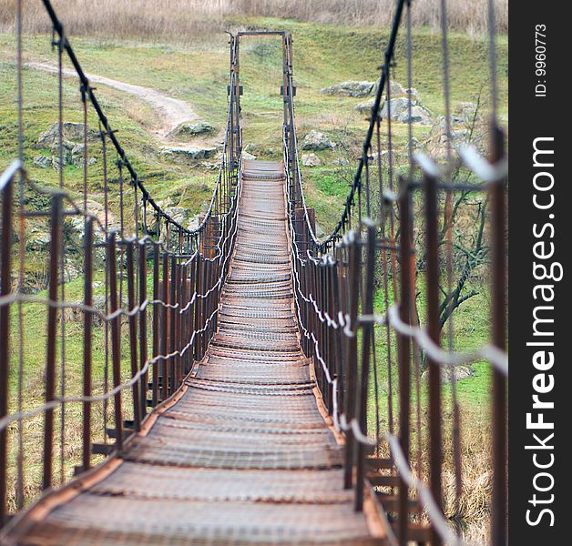 Old rusty metal suspension bridge in  countryside