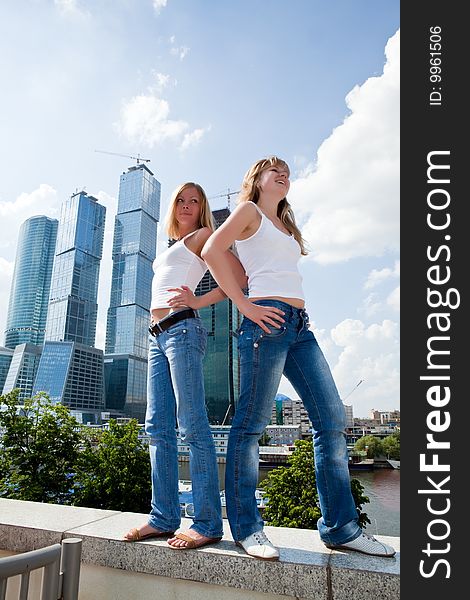 Two beautiful girls against skyscrapers and the blue sky