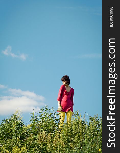 Girl goes on the grass against the background of blue sky. Girl goes on the grass against the background of blue sky.