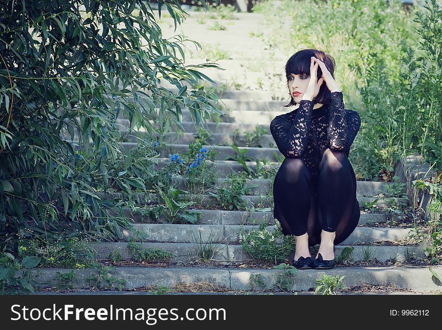 Stylish girl sits on the stair in the park. Stylish girl sits on the stair in the park.
