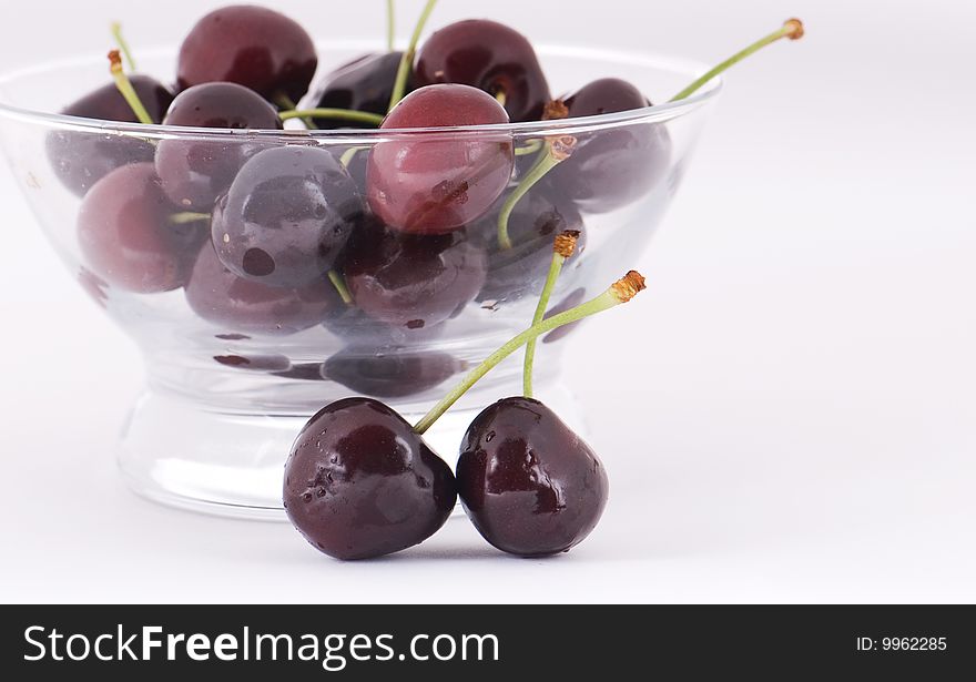 Ripe sweet cherry in a glass on a white background