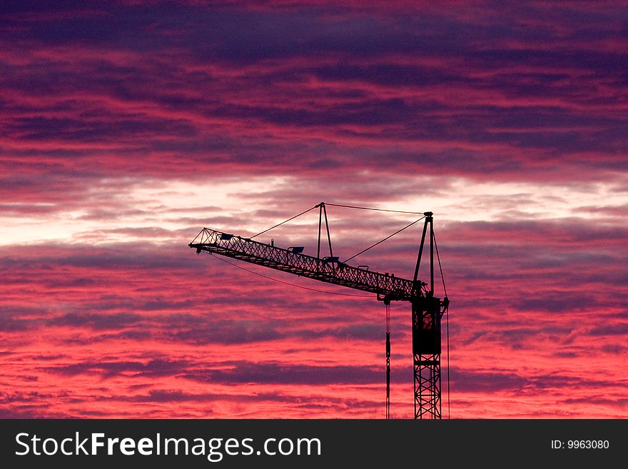 A construction crane in front of a dramatic sunset, blue and red sky. A construction crane in front of a dramatic sunset, blue and red sky