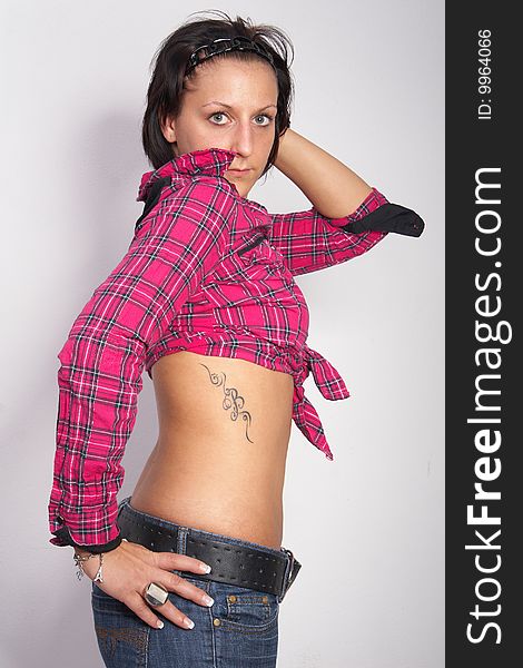 Portrait of a young woman wearing a pink shirt and ripped blue jeans. She is showing off her beautiful tattoo. Isolated over white. Portrait of a young woman wearing a pink shirt and ripped blue jeans. She is showing off her beautiful tattoo. Isolated over white.
