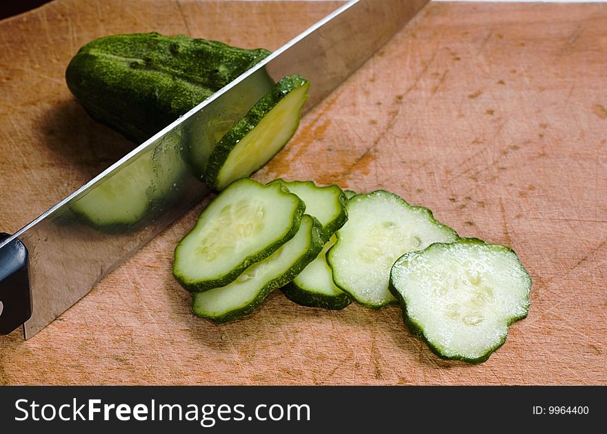 Knife and cucumber on wood table with selective focus