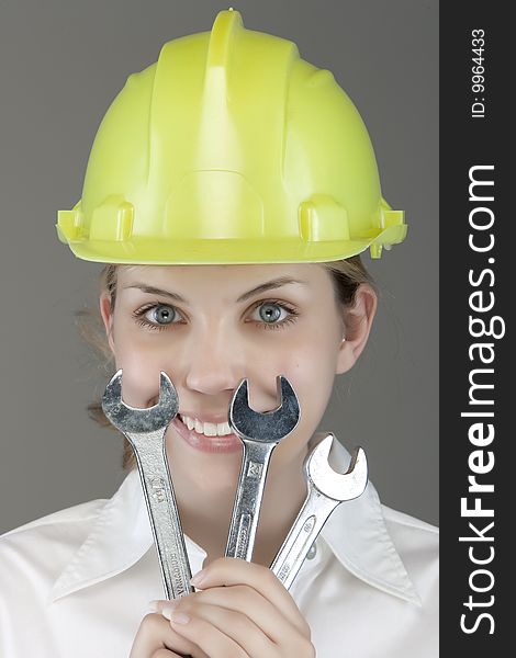 Pretty girl with helmet and wrench over white background