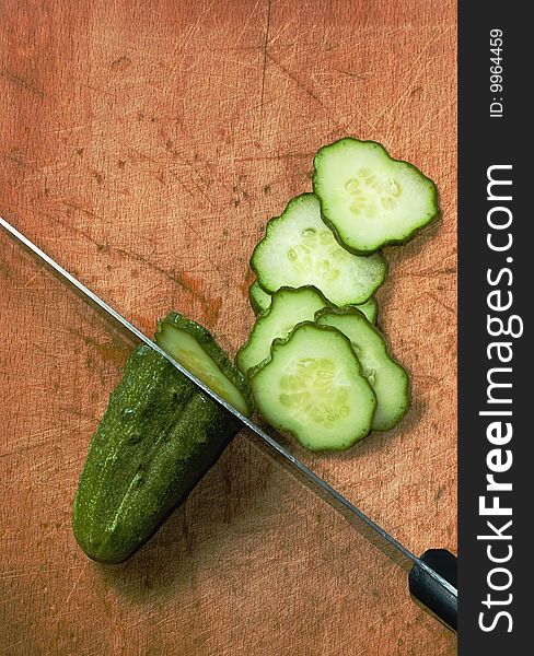 Cucumber and kitchen knife on wood table with selective focus. Cucumber and kitchen knife on wood table with selective focus