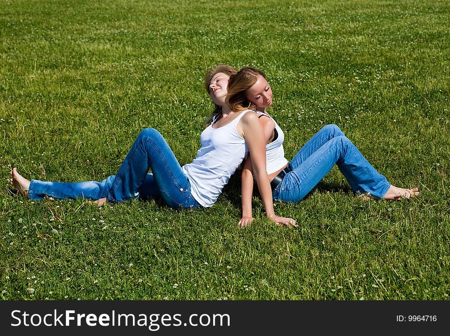 Two girls have a rest on a green grass. Two girls have a rest on a green grass