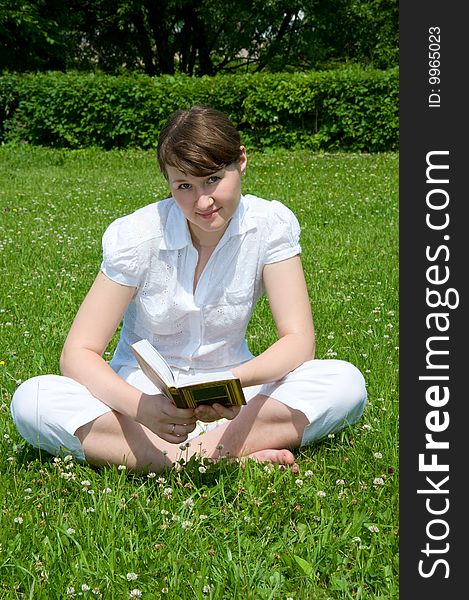 Attractive woman is sitting on grass with book. Attractive woman is sitting on grass with book