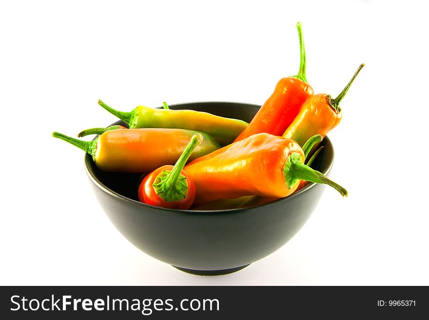 Mixed red and green chillis in a black bowl with clipping path on a white background