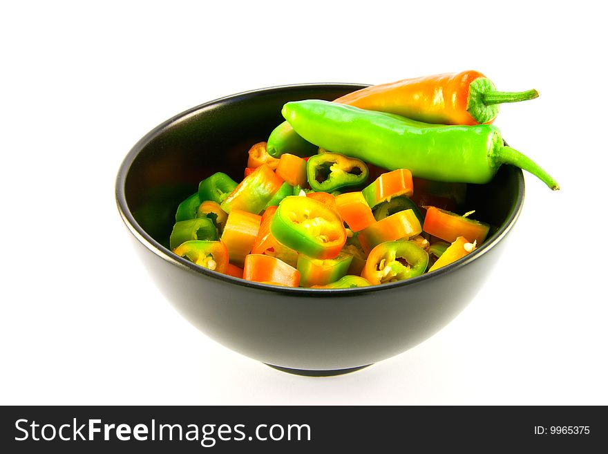 Two chillis and chopped chillis in a black bowl with clipping path on a white background