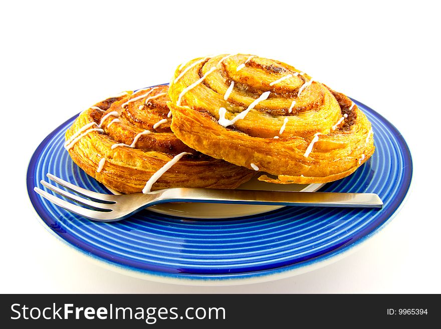 Two cinnamon buns on a blue plate with fork with clipping path on a white background