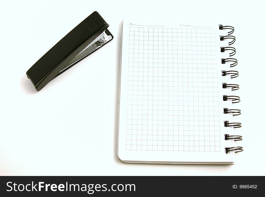 Writing-book and stapler nearby on a white background