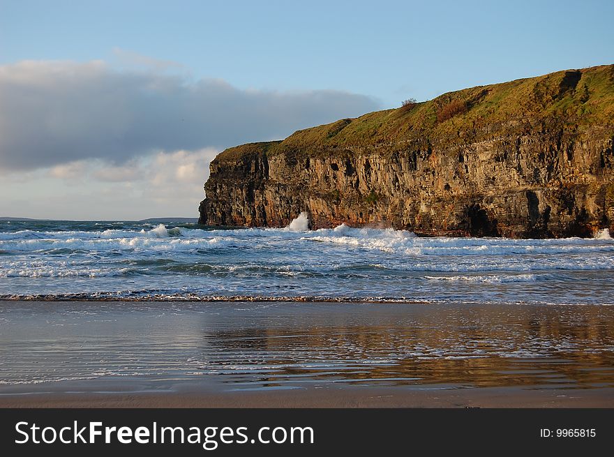 Ballybunion Soltice Cliff Reflection with blue sky clouds and surf. taken on mid-summers day