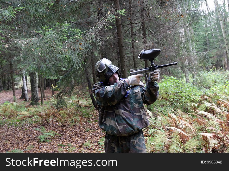 The man plays in paintball in a coniferous forest