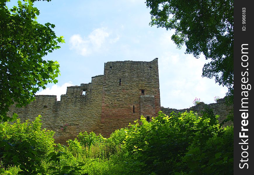 A medieval stone castle ruin is framed by trees as nature relaims it. A medieval stone castle ruin is framed by trees as nature relaims it