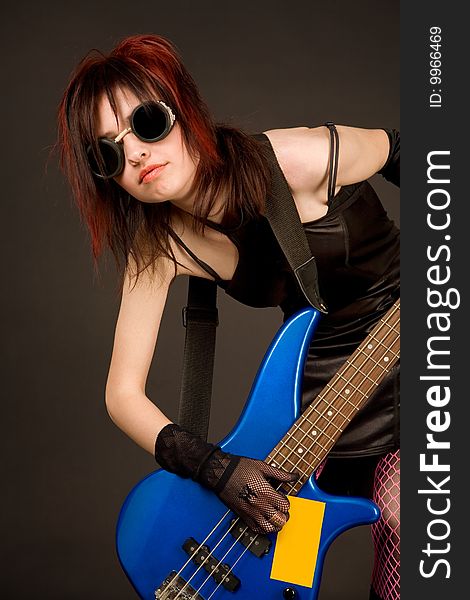 Industrial girl with bass guitar, studio shot over black background