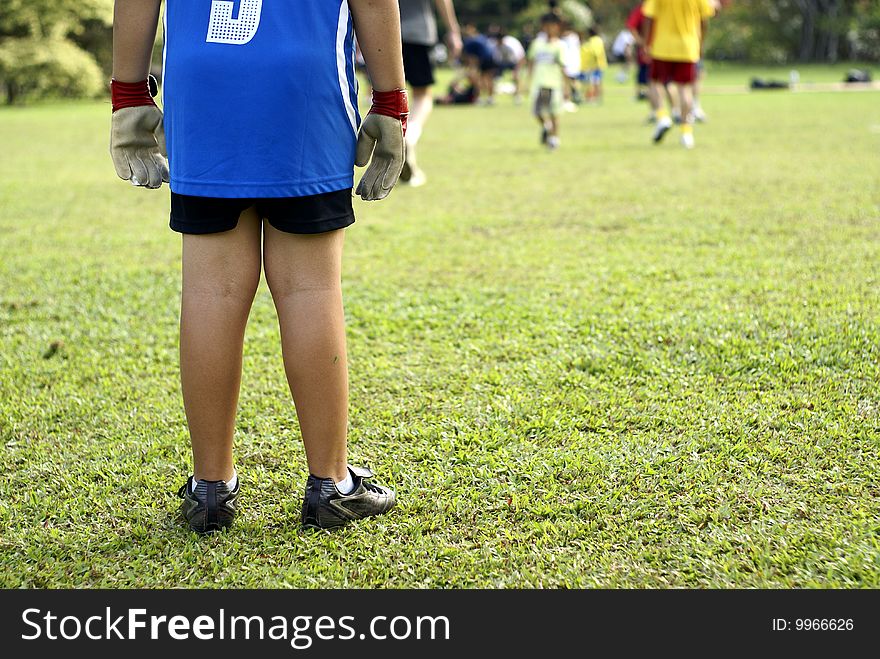 Park soccer game,  focus on young goalkeeper with players in background. Park soccer game,  focus on young goalkeeper with players in background