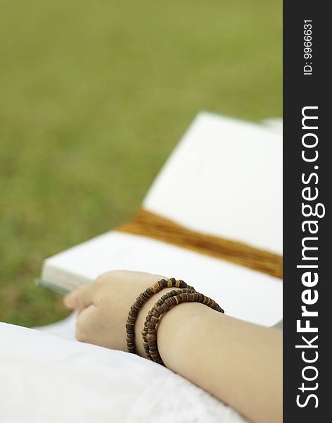 Reading book outdoors with green grass background