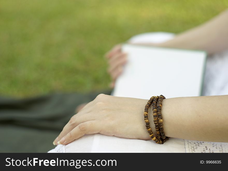 Reading book outdoors with green grass background