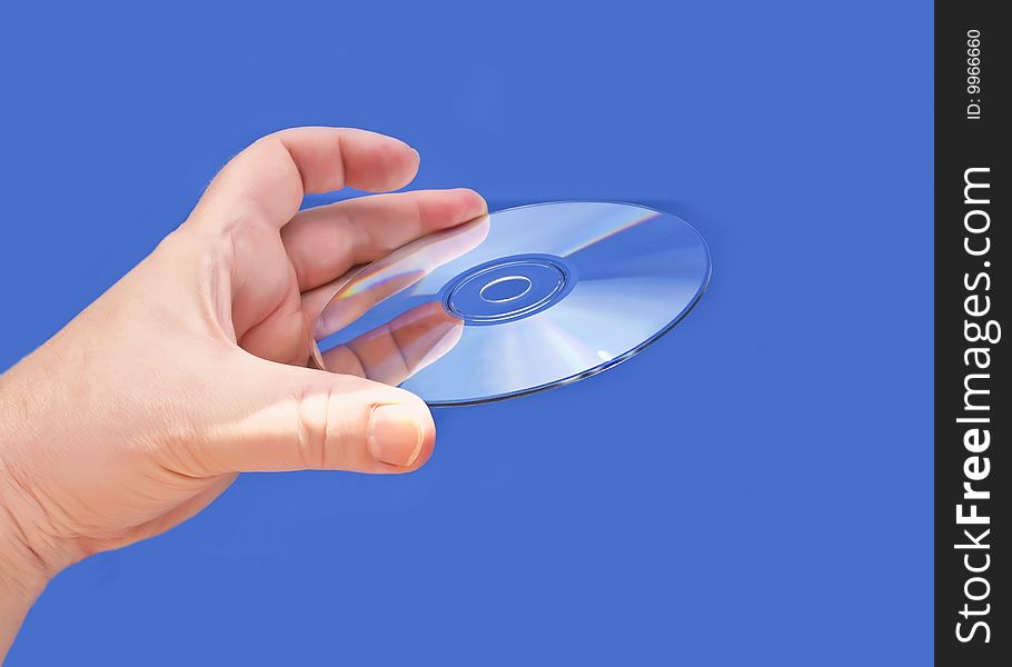 A hand holding a CD or DVD media against a blue background. A hand holding a CD or DVD media against a blue background